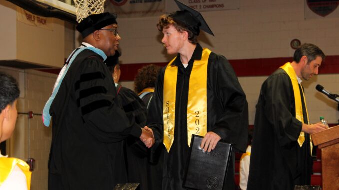 Aiden Derieux, now a graduate of SandHoke Early College High School in Raeford, shakes the hand of Hoke County Schools Superintendent Kenneth Spells Friday night, at McDonald Gymnasium at Hoke High School. Aiden was one of 119 graduates in the class of '24. Photo courtesy Alison Jones / Hoke County Schools
