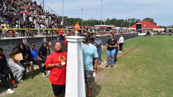 Hoke County Schools held its annual Special Olympics event on Friday at Raz Autry Stadium. This was the first full Special Olympics since 2020, with more 90 student athletes competing and more than 220 participating overall. Pictured is Jalen Bowers and his family bringing in the Special Olympics torch. Hal Nunn for North State Journal